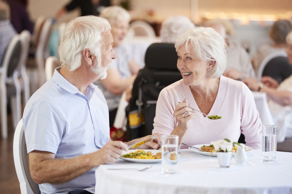 Male and female senior living residents enjoying a meal in the Traditions of Saginaw senior community dining room