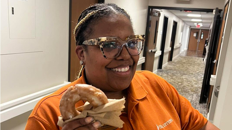 Traditions of Saginaw employee smiling while holding a donut