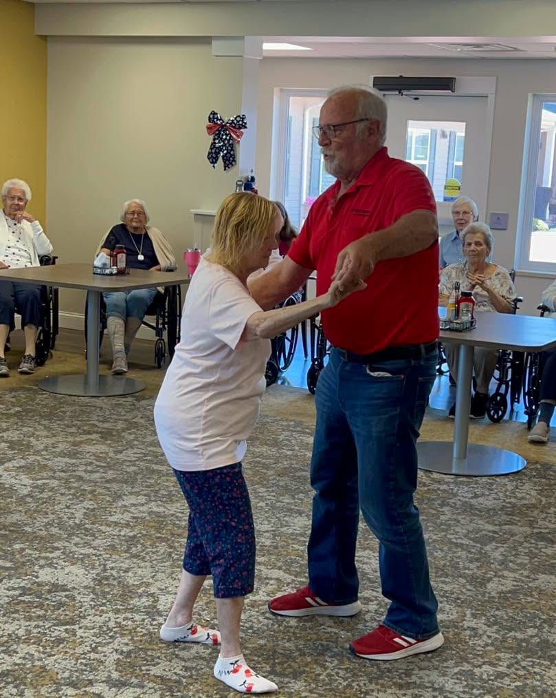 A resident dances with a guest as neighbors watch at Traditions of Saginaw in Saginaw, Michigan.